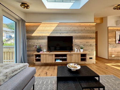 Perfekt für Regentage: gemütlich einen Film schauen und entspannen Modernes Wohnzimmer mit Holzverkleidung, Fernseher und gemütlicher Sitzecke.