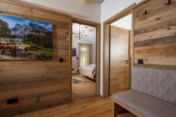 Der Flur empfängt Sie mit einer Sitzbank und viel Stauraum für Ihre Jacken und Mäntel Holzvertäfelter Flur mit Türen, einem Bild an der Wand und Sicht auf ein Schlafzimmer.