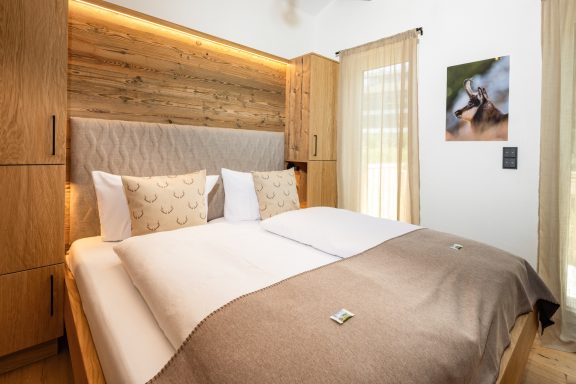 Das gemütliche Schlafzimmer „Gams“ lädt Groß und Klein zum Kuscheln ein Helle, gemütliche Schlafzimmer mit Doppelbett und Holzverkleidung.