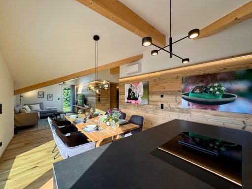 Der freistehende Küchenblock integriert sich nahtlos in den Essbereich Moderne Wohnküche mit Holzdecke, Essbereich und stilvoller Dekoration an der Wand.