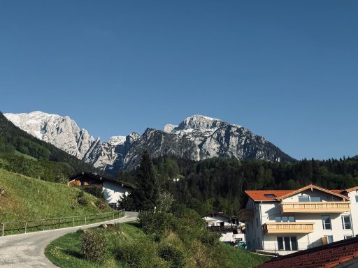 Berglandschaft mit schneebedeckten Gipfeln und Häusern im Vordergrund unter klarem Himmel.