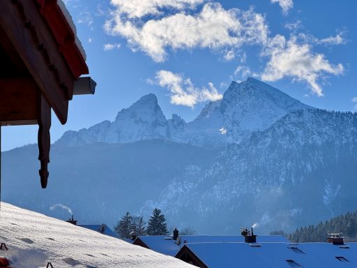 Vom großen Balkon genießen Sie einen Blick auf den Watzmann Schneebedeckte Berge unter blauem Himmel, gesehen von einem Dachrand aus.
