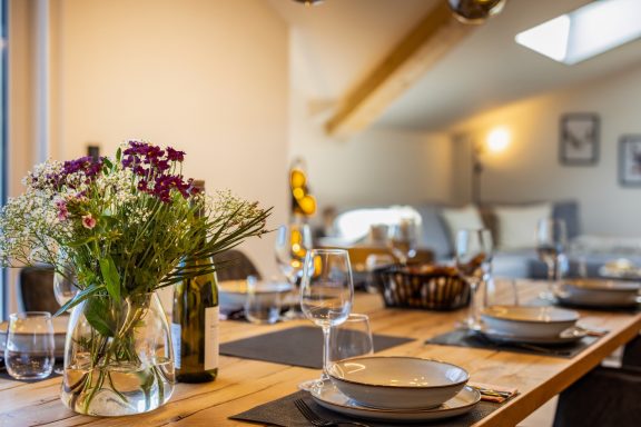 Für alle Gäste ist ausreichend Geschirr vorhanden Ein gedeckter Tisch mit Blumen, Gläsern und Geschirr in einem stilvollen Raum.