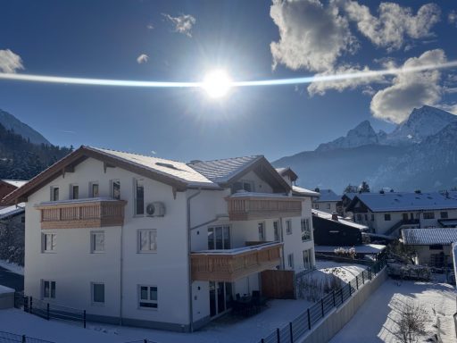 Das Gipfelglück befindet sich im Dachgeschoss und hat zwei Balkone Winterlandschaft mit schneebedecktem Haus, Bergen im Hintergrund und sonnigem Himmel.