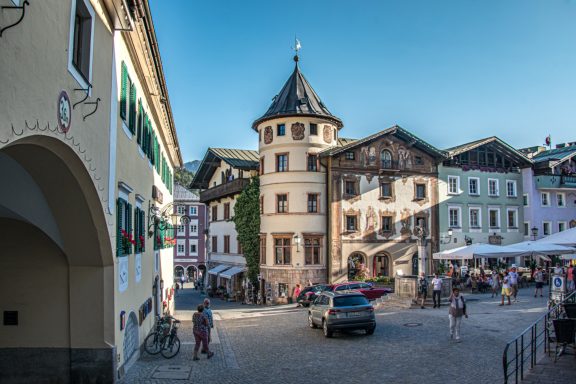 Stadtplatz mit historischem Gebäude und Außenterrassen unter klarem Himmel.