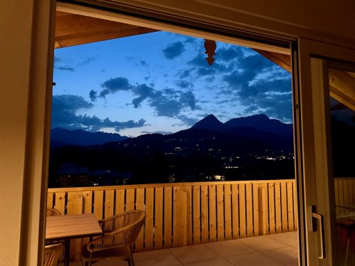 An lauen Sommerabenden kann man auf dem großen Balkon die letzten Sonnenstrahlen bis zum Sonnenuntergang genießen Blick auf Berge und Himmel bei Dämmerung von einem Balkon aus.