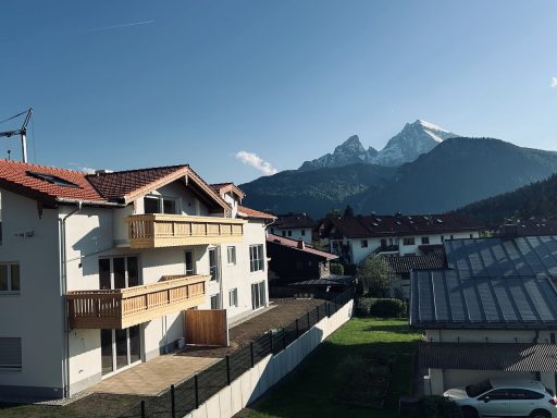 Berglandschaft mit schneebedeckten Gipfeln und modernen Wohngebäuden im Vordergrund.