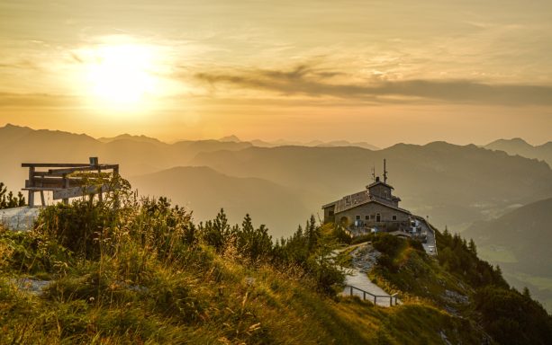Berglandschaft bei Sonnenuntergang mit Aussichtspunkt und Hüttenstruktur.