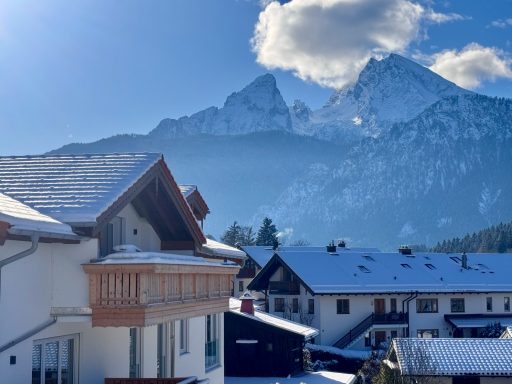 Blick auf den großen Balkon mit dem Watzmann im Hintergrund Schneebedeckte Berge im Hintergrund mit Häusern im Vordergrund.