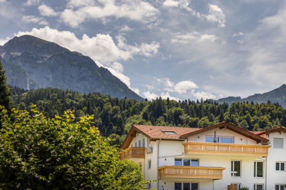 Das Gipfelglück befindet sich im Dachgeschoss und verfügt über zwei Balkone Berglandschaft mit Wolken und einem modernen Haus im Vordergrund.